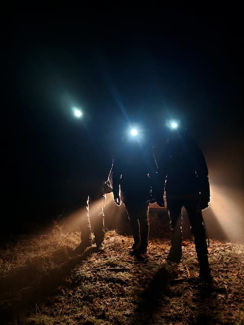 Nachtelijke navigatie-oefening met hoofdlampen tijdens wildernis-overlevingstraining.